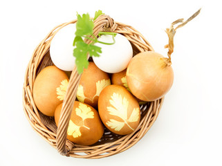 Wicker basket with colored eggs onion and parsley  isolated