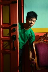 Young asian teen peeking and sneaking in into a living room