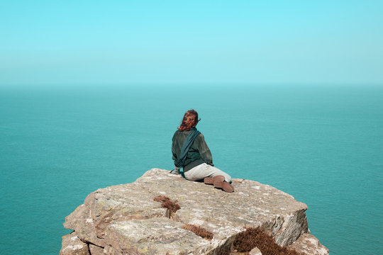 Young woman sitting on cliff by the sea
