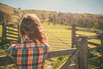 Young woman by a fence on a ranch