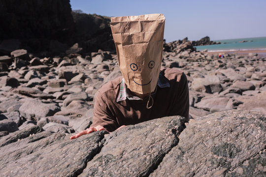 Man with paperbag over his head on the beach