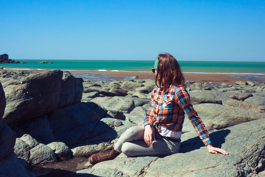 Young woman sitting on a rocky beach
