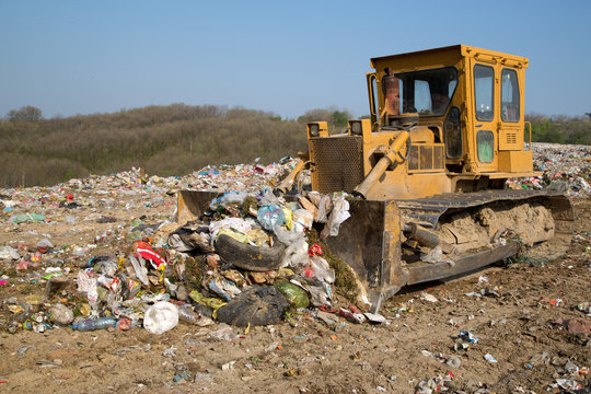 The Old Bulldozer Moving Garbage In A Landfill