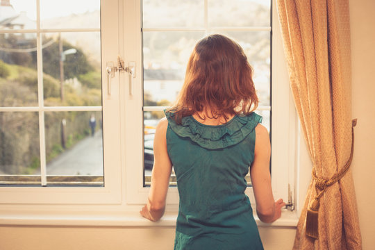 Young woman in dress looking out the window