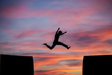 man jumping a gap in sunset sky