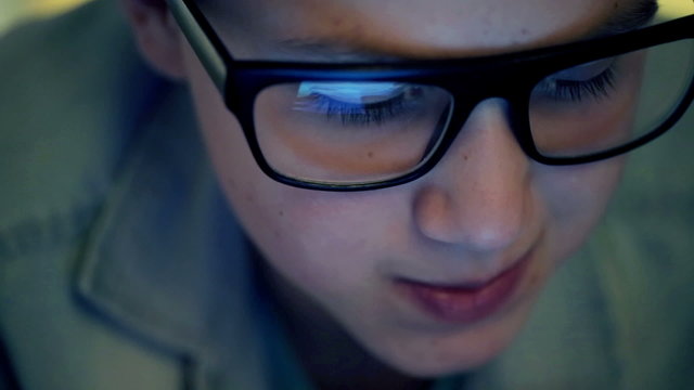 Boy in glasses watching something on tablet computer