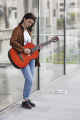 Fototapeta na wymiar Girl playing guitar in the city