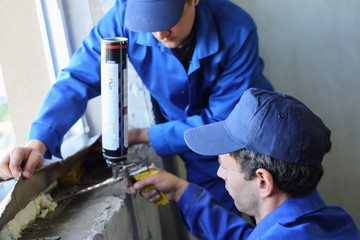 Two workers use mounting foam