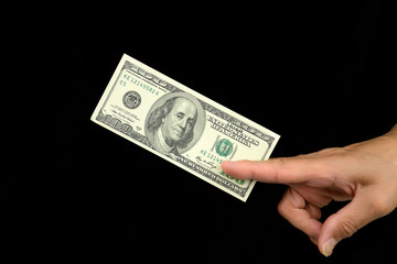 Human hand delivers bill hundred dollars, on a black background
