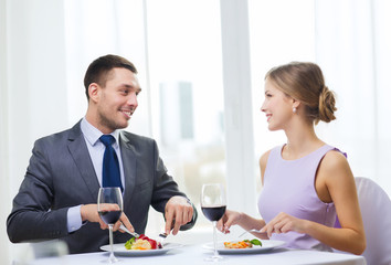 smiling couple eating main course at restaurant
