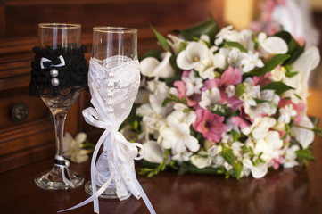 Two wedding glasses and bridal bouquet on stone in summer garden