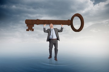 Composite image of businessman carrying large key