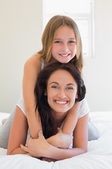 Girl sitting on mother in bedroom