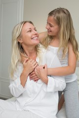 Mother and daughter looking at each in bed