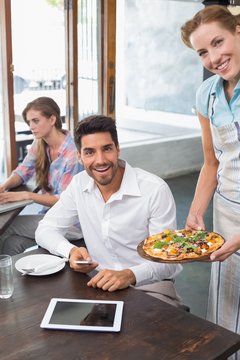Waitress giving pizza to man at coffee shop