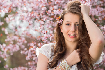 Girl with braces posing near blossoming tree