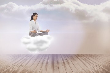 Composite image of businesswoman sitting in lotus pose