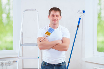 handsome young painter with crossed arms holding blue paintbrush