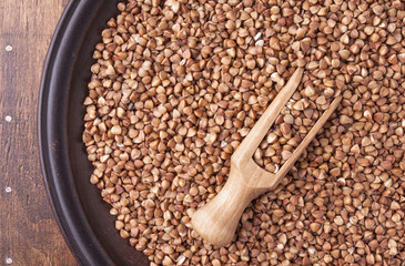Organic buckwheat groats in plate on dark wood background