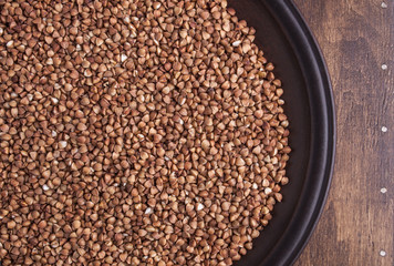 Organic buckwheat groats in plate on dark wood background