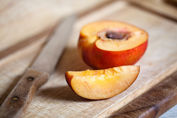 Sliced peach and knife placed on wooden plate