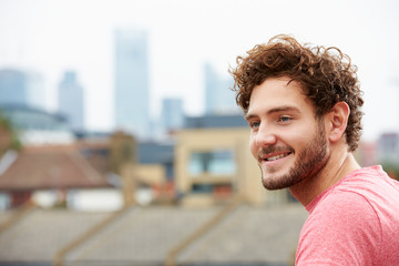 Young Man Looking Out Over City From Roof Terrace