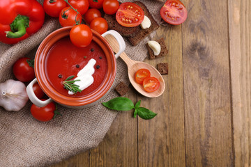 Tasty tomato soup and vegetables on wooden table