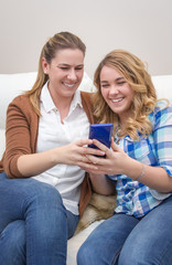 Mother and daughter laughing when looking at phone