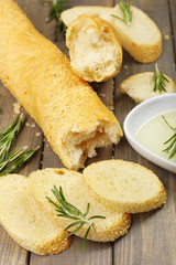 Fresh bread with olive oil and rosemary on wooden table