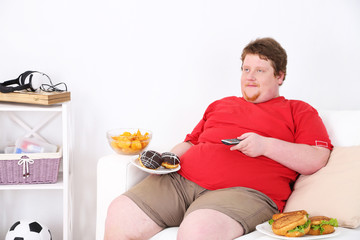 Lazy overweight male sitting with fast food