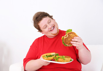 Fat man eating tasty sandwich on home interior background