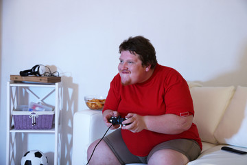 Fat man playing video games on home interior background