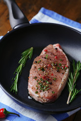 Raw meat steak with herbs and spices on pan, close-up