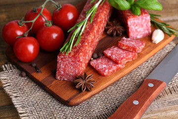 Tasty salami sausage and spices on wooden background