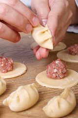 Cook hands sculpt Asian gyoza dumplings vertical
