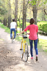 Naklejka premium Young couple with bicycles in park