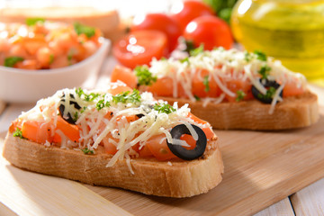 Delicious bruschetta with tomatoes on cutting board close-up