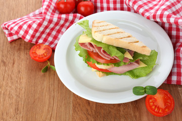 Tasty sandwich with ham on wooden table