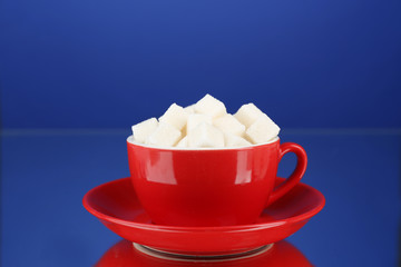 Sugar in cup on blue background
