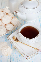 Cup of tea with meringues on table close-up