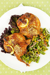 Roasted quails with vegetables on plate, on wooden background