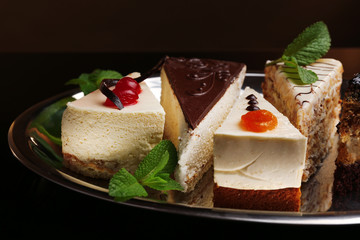 Assortment of pieces of cake, on dark background © Africa Studio