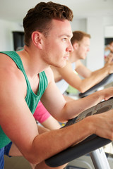 Obraz premium Two Young Men Training In Gym On Cycling Machines Together