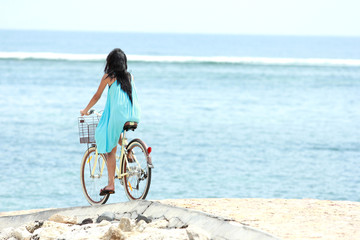 Fototapeta na wymiar woman having fun and smiling riding bicycle at the beach