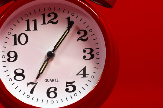 A red vintage alarm clock on a red background