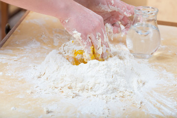 Girl is mixing by hand the water, flour and an egg