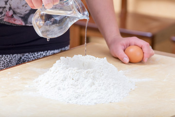 Girl is pouring water into the flour
