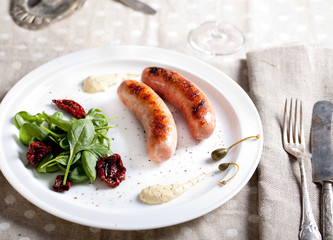 Grilled sausages with salad on a white plate