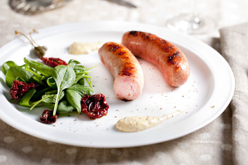 Grilled sausages with salad on a white plate