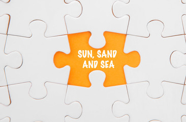 Missing piece puzzle revealing the SUN, SAND AND SEA words